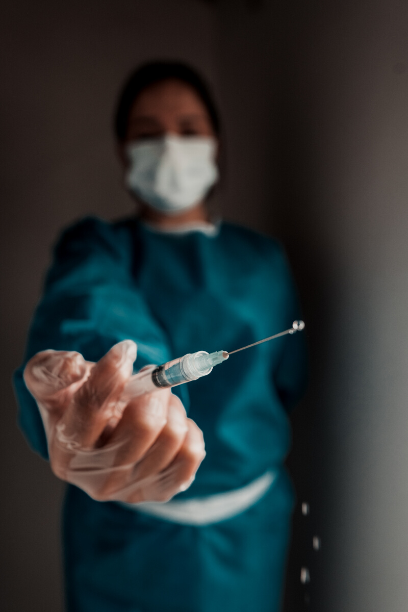 Unrecognizable doctor showing syringe with pouring medicine drops